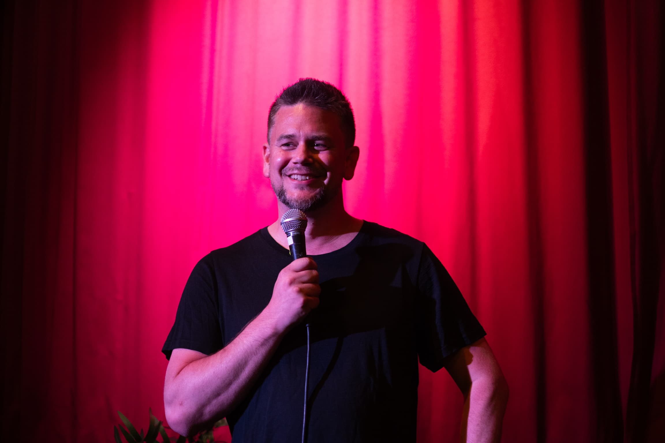 Snorre Bue smiler på scenen med mikrofon